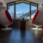 Schütthof_VulcanoSpa_Ruheraum_2 A room with four red and white bucket seats arranged in a square. With a view of the mountains.